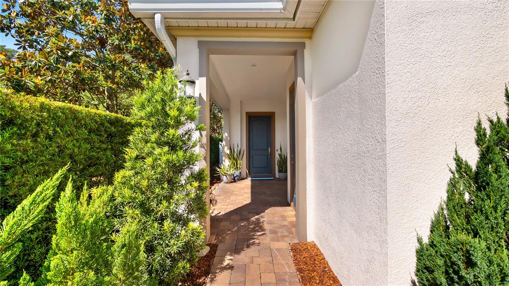 A paved walkway leads to a covered entryway with a dark blue front door — 1500 RACKETS COURT, LAKE MARY, FL