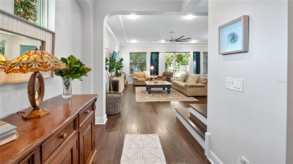 A wooden console table sits in a hallway leading to a living room with hardwood floors — 1500 RACKETS COURT, LAKE MARY, FL