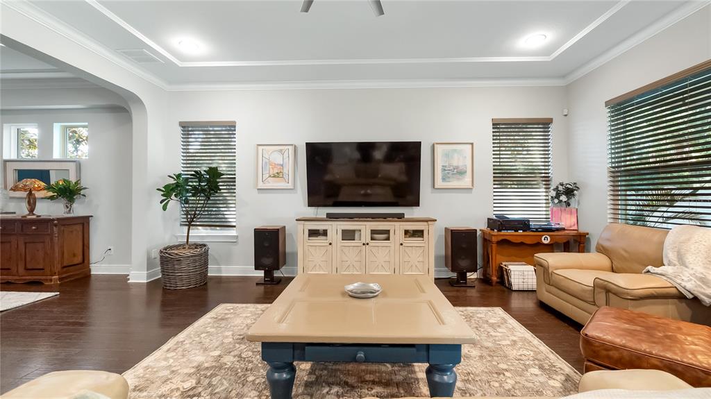 A living room features a wall-mounted television, wooden media console, speakers, and hardwood flooring — 1500 RACKETS COURT, LAKE MARY, FL