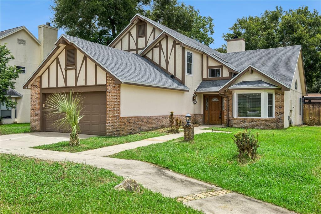A two-story Tudor-style house with a brown garage, brick accents, and a front walkway — 307 BENT WAY LANE, LAKE MARY, FL