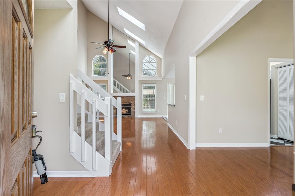 An entryway with hardwood floors, a carpeted staircase, and a vaulted ceiling with skylights — 307 BENT WAY LANE, LAKE MARY, FL