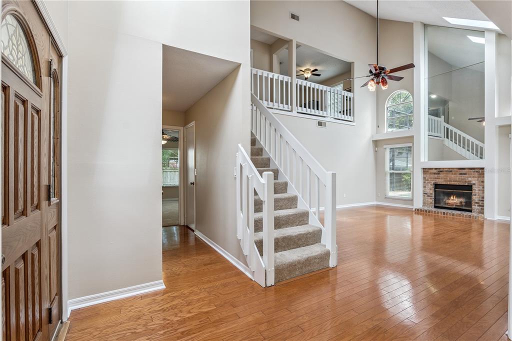 An entryway with hardwood floors, a carpeted staircase, and a view into a living room — 307 BENT WAY LANE, LAKE MARY, FL