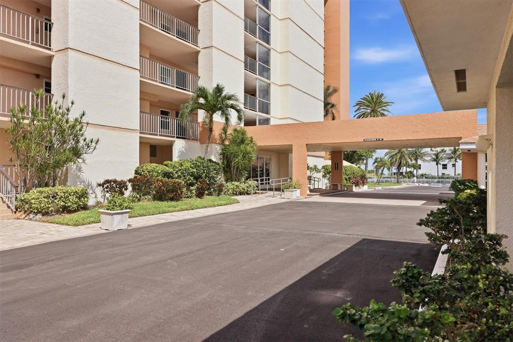 A multi-story apartment building features a covered driveway entrance and landscaped grounds — 4401 GULF OF MEXICO DRIVE UNIT 907, LONGBOAT KEY, FL