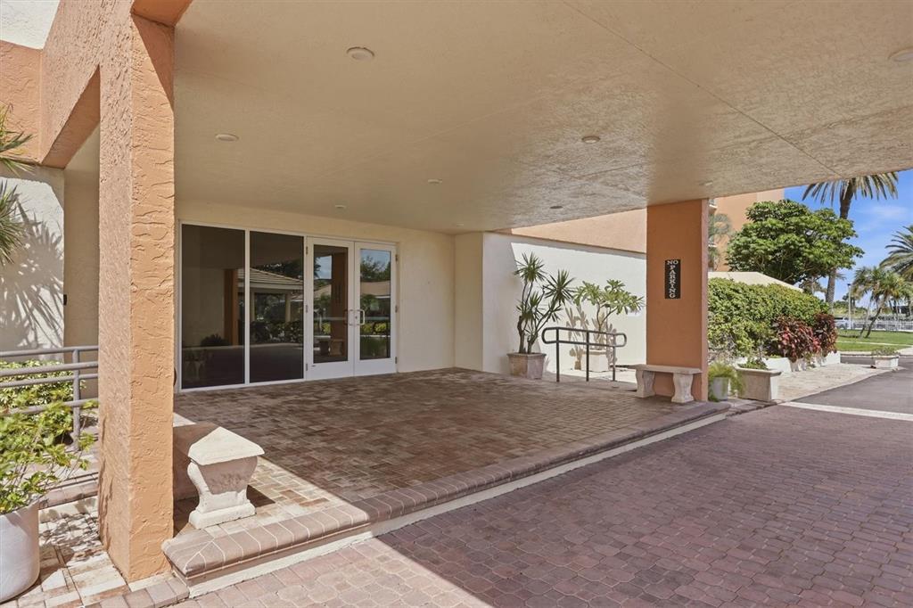 A covered brick entryway leads to glass double doors at the front of a building — 4401 GULF OF MEXICO DRIVE UNIT 907, LONGBOAT KEY, FL