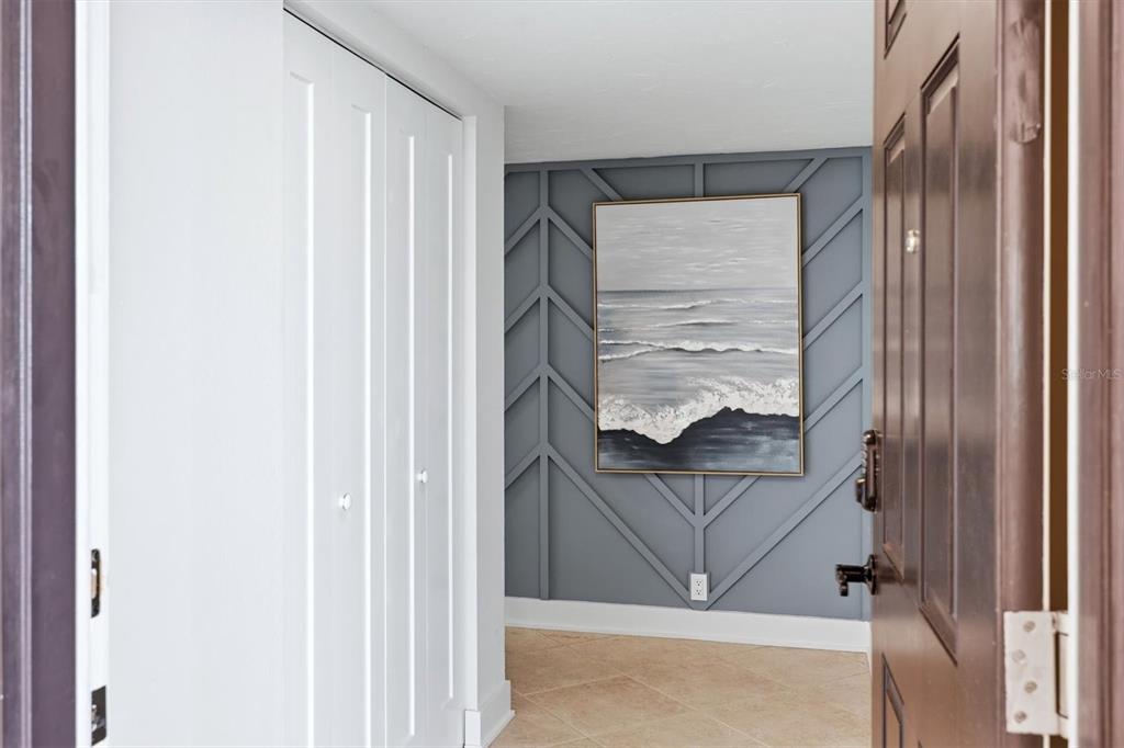 An entryway features a gray accent wall with geometric molding, a seascape painting, and closet doors — 4401 GULF OF MEXICO DRIVE UNIT 907, LONGBOAT KEY, FL