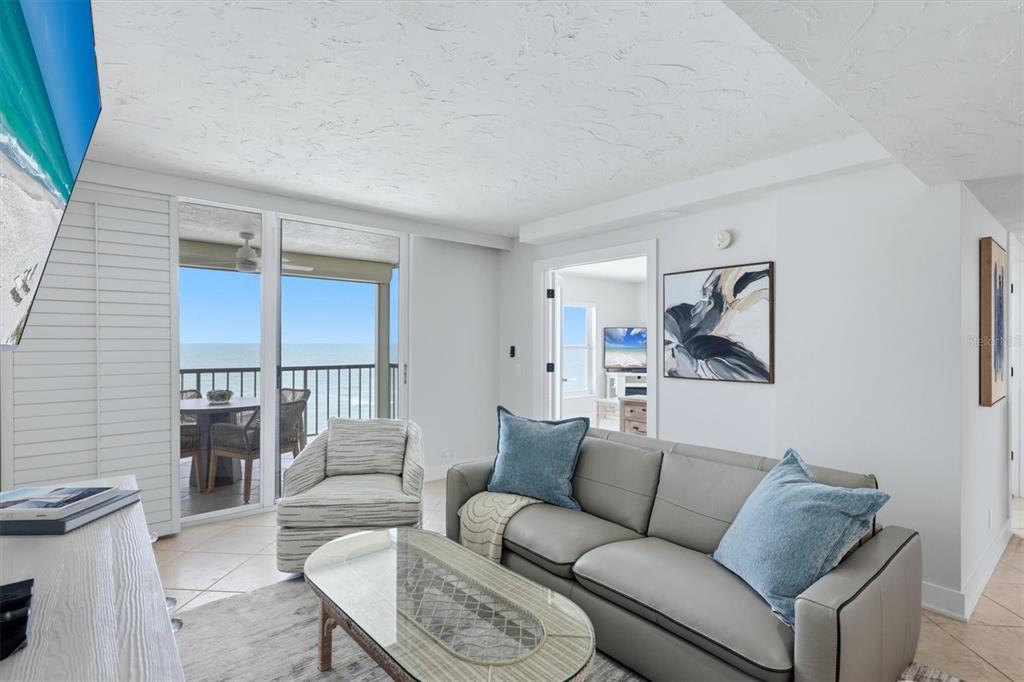 A living room with a grey sofa, glass coffee table, and a balcony overlooking the ocean — 4401 GULF OF MEXICO DRIVE UNIT 907, LONGBOAT KEY, FL