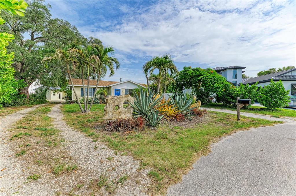 A gravel driveway leads to a single-story house with palm trees and landscaping in front — 1300 LOMA LINDA COURT, SARASOTA, FL