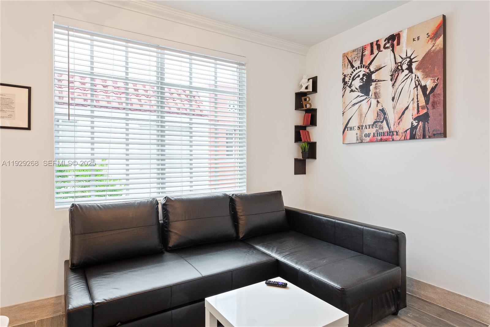 A living room features a black sectional sofa, a white coffee table, and wall art — 1355 Drexel Ave, Miami Beach FL 33139, MIAMI BEACH, FL