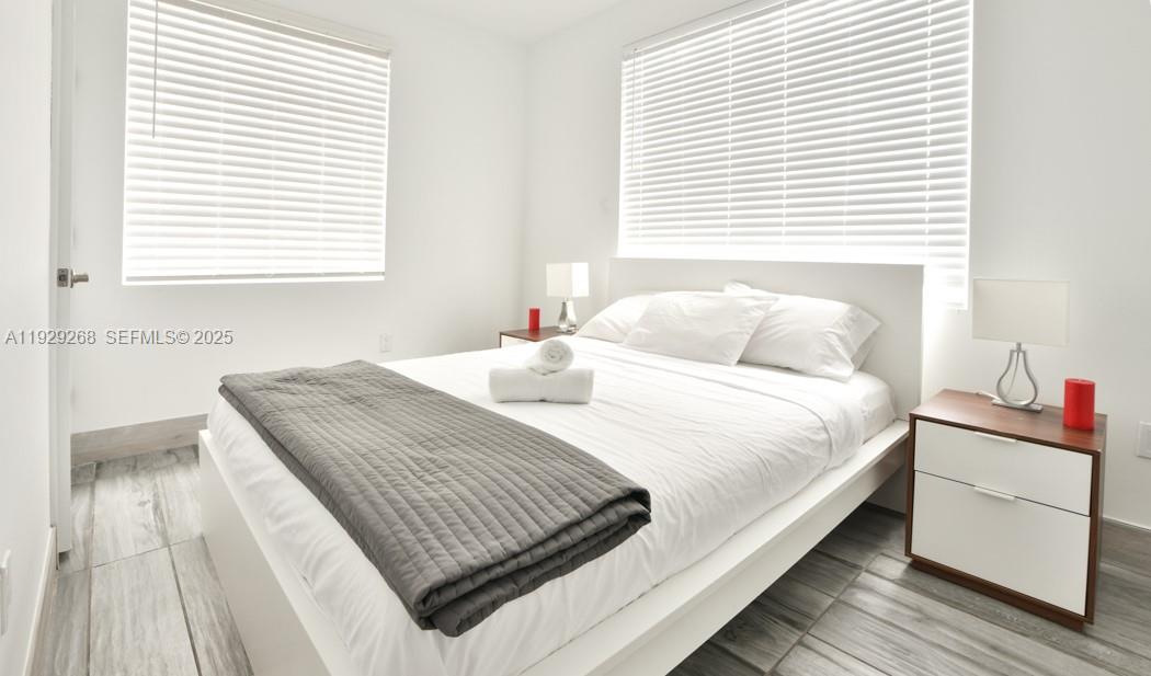 A bedroom features a white bed with a gray throw, two nightstands, and window blinds — 1355 Drexel Ave, Miami Beach FL 33139, MIAMI BEACH, FL
