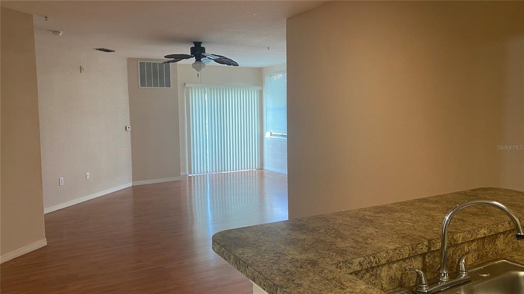 A view from a kitchen sink looking into an open living area with wood flooring — 5550 E MICHIGAN STREET UNIT 1306, ORLANDO, FL