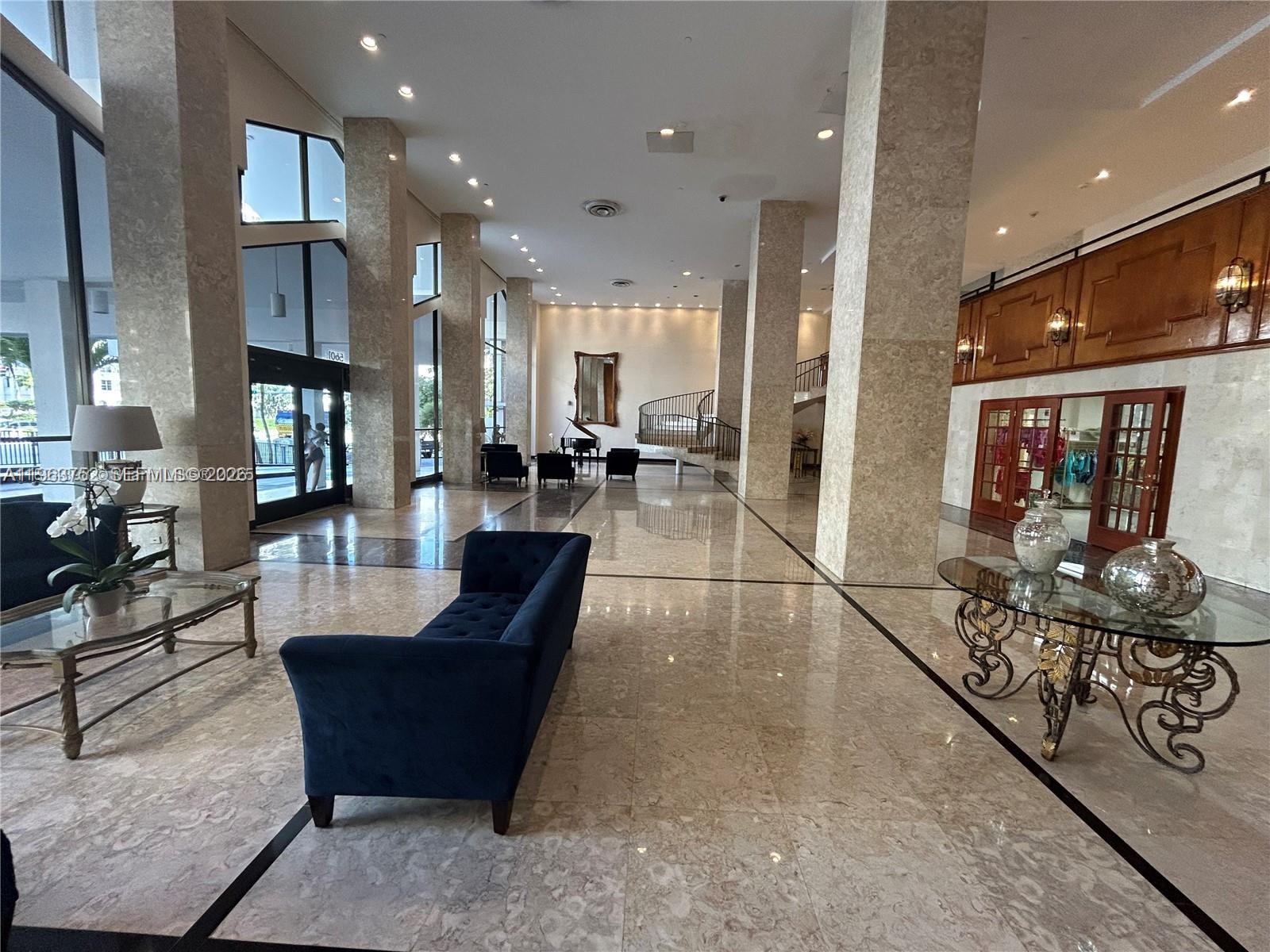 A spacious lobby features marble floors, large stone columns, and a blue velvet sofa — 5601 Collins Ave # 9, Miami Beach FL 33140, MIAMI BEACH, FL
