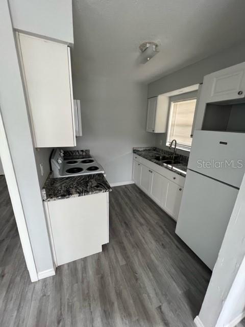 A kitchen features white cabinets, dark granite countertops, stainless steel appliances, and light wood flooring — 13106 LEISUREWOOD PLACE UNIT 102, TAMPA, FL