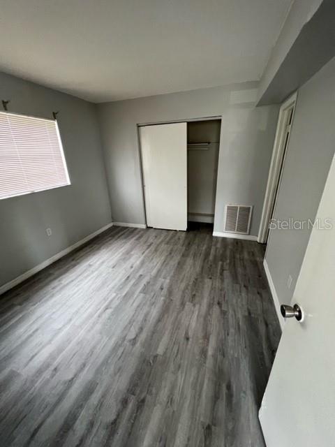 An empty bedroom features gray walls, wood-look flooring, a window with blinds, and a closet — 13106 LEISUREWOOD PLACE UNIT 102, TAMPA, FL