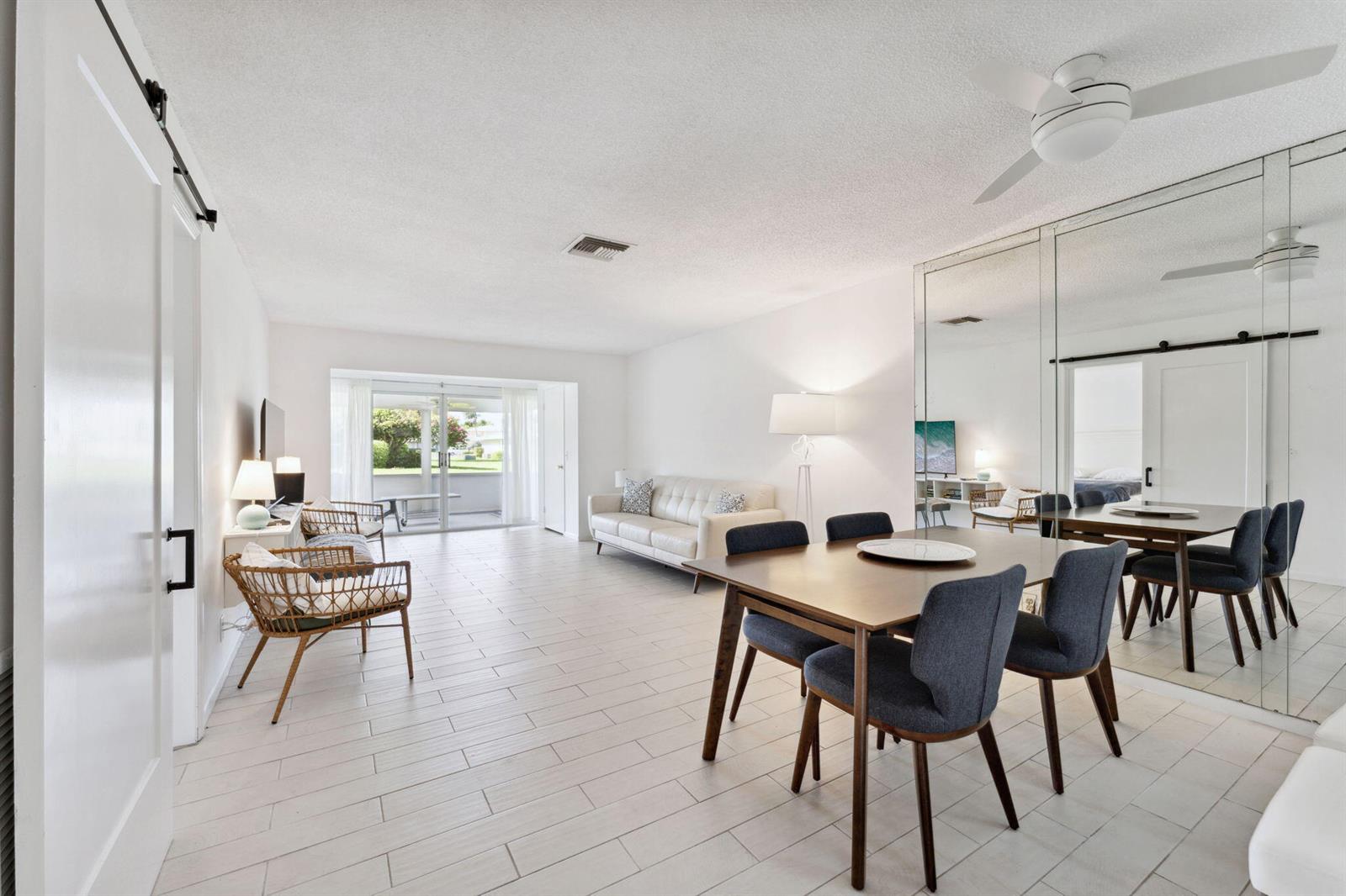 A bright living and dining area features white tile floors, a mirrored wall, and furniture — 1120 Cactus Terrace # c, Delray Beach FL 33445, DELRAY BEACH, FL