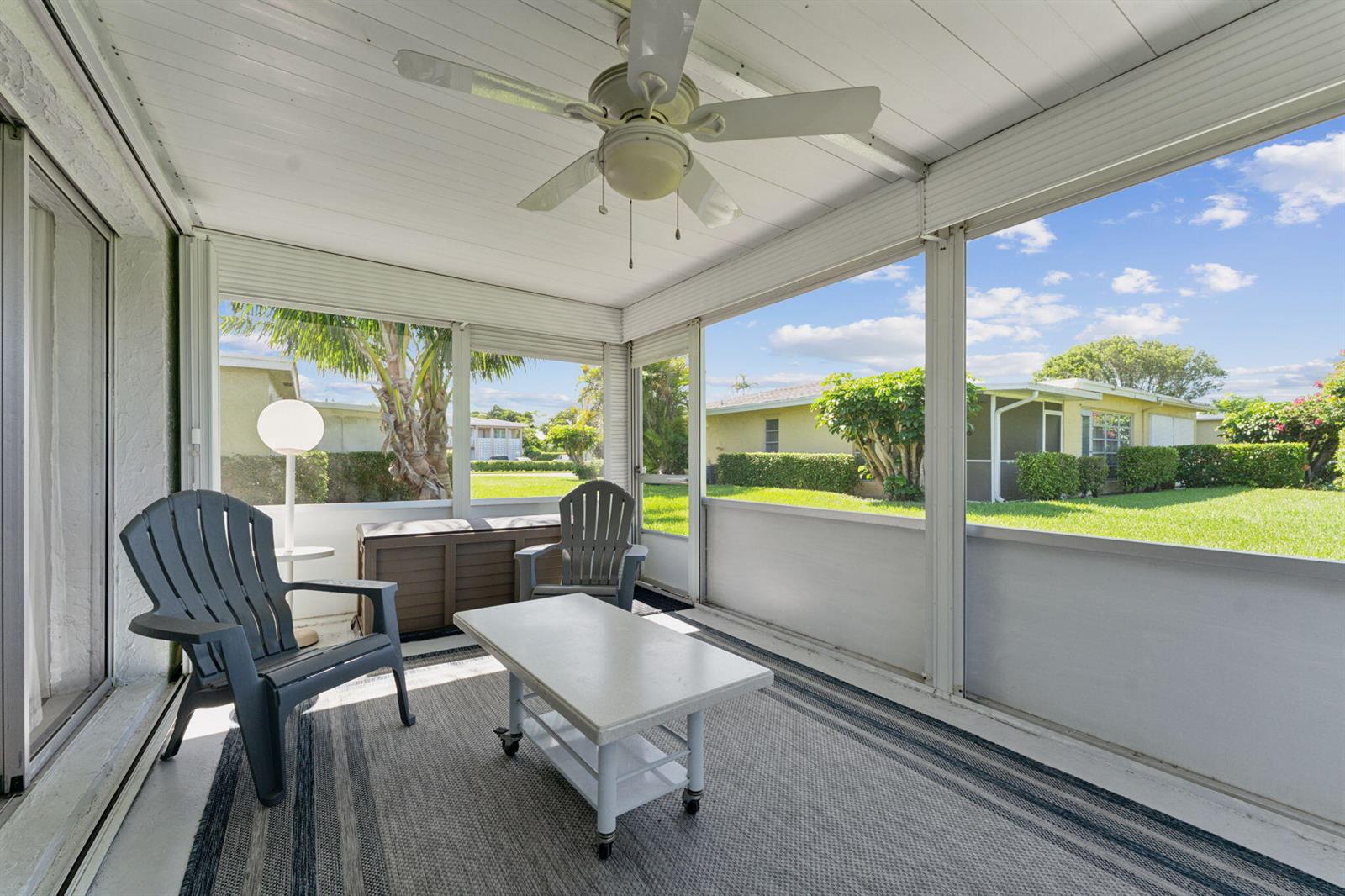 A screened-in porch features a ceiling fan, two chairs, a coffee table, and outdoor views — 1120 Cactus Terrace # c, Delray Beach FL 33445, DELRAY BEACH, FL
