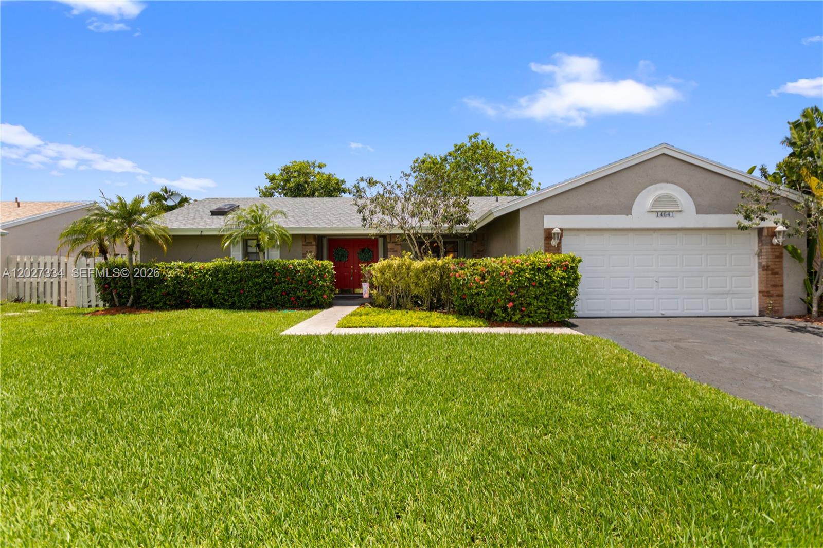 A single-story house features a red front door, a white garage, and a manicured lawn — 14641 Kirsten Ct, Davie FL 33325, DAVIE, FL