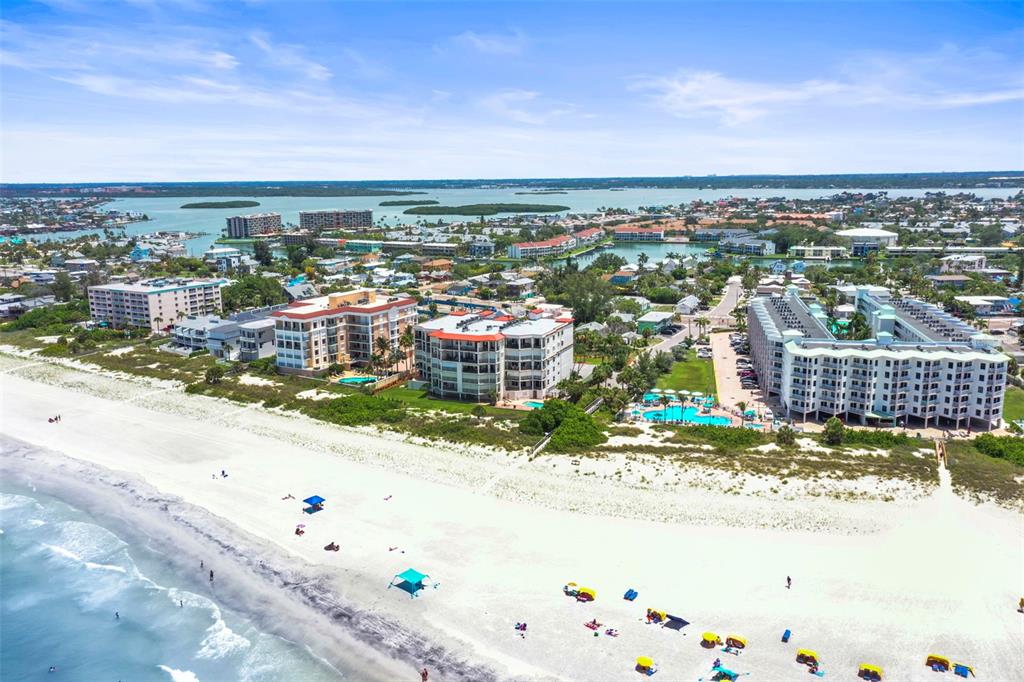 An aerial view shows beachfront condominiums with swimming pools along a sandy coastline — 200 121ST AVENUE UNIT 103, TREASURE ISLAND, FL