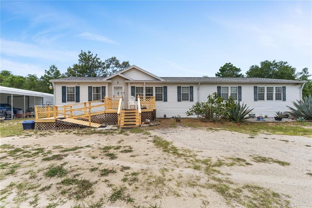 A single-story manufactured home with white siding, a front deck, and a wheelchair ramp — 13020 WEBSTER STREET, BROOKSVILLE, FL