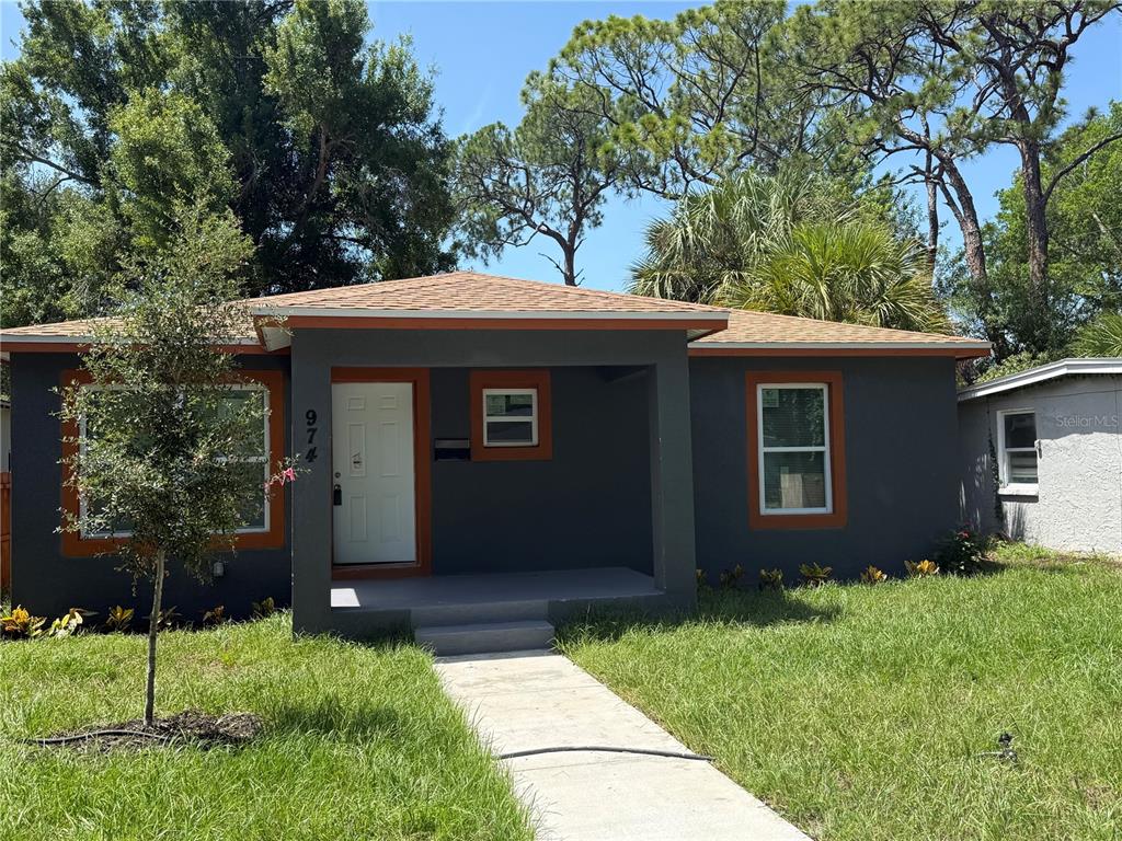 A single-story house with dark gray stucco walls, orange trim, and a covered front porch — 974 23RD AVENUE S, ST PETERSBURG, FL