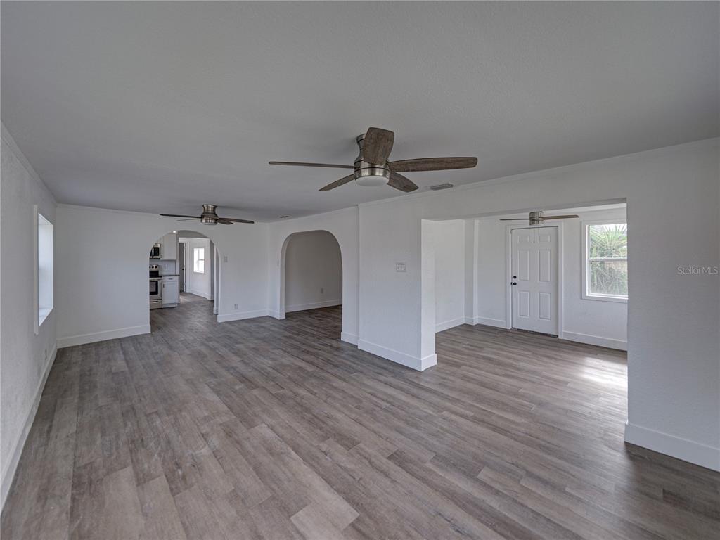 An open-concept living area features white walls, gray wood-look flooring, and three ceiling fans — 602 E LAURA STREET, PLANT CITY, FL