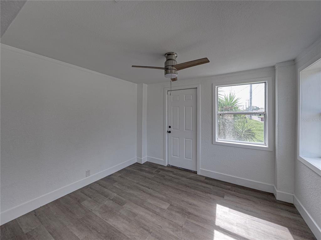 An empty room with white walls, wood-look flooring, a ceiling fan, and a single door — 602 E LAURA STREET, PLANT CITY, FL