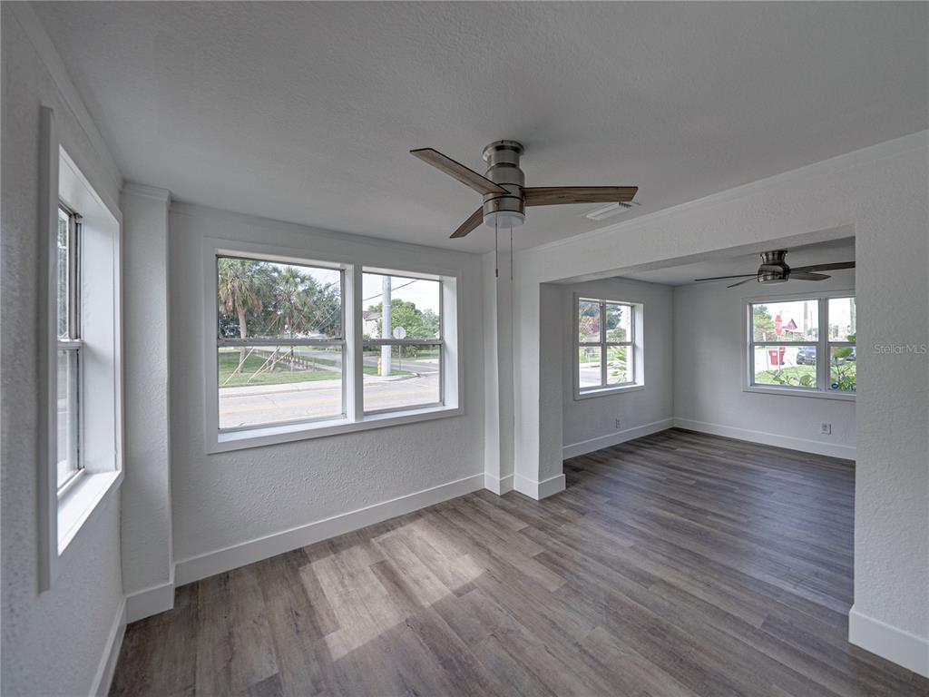 An interior view shows two connected rooms with gray wood-look flooring, white walls, and ceiling fans — 602 E LAURA STREET, PLANT CITY, FL