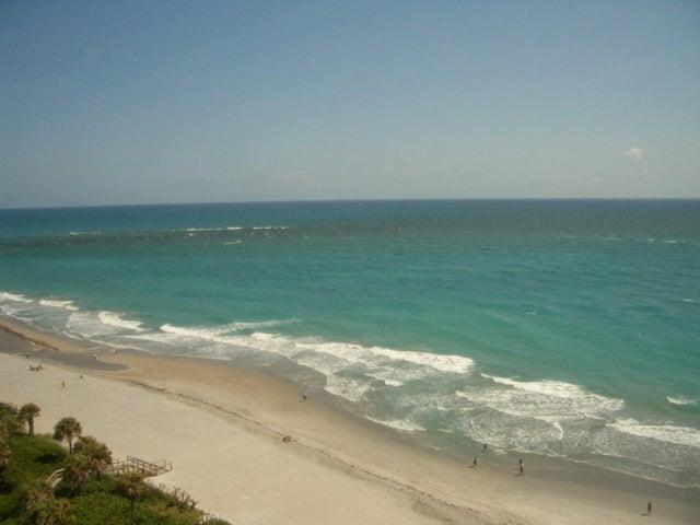 An elevated view of a sandy beach with turquoise ocean waves and palm trees below — 300 Ocean Trail Way # 1302, Jupiter FL 33477, JUPITER, FL
