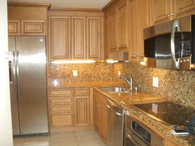 A kitchen features wood cabinets, granite countertops, stainless steel appliances, and under-cabinet lighting — 300 Ocean Trail Way # 1302, Jupiter FL 33477, JUPITER, FL