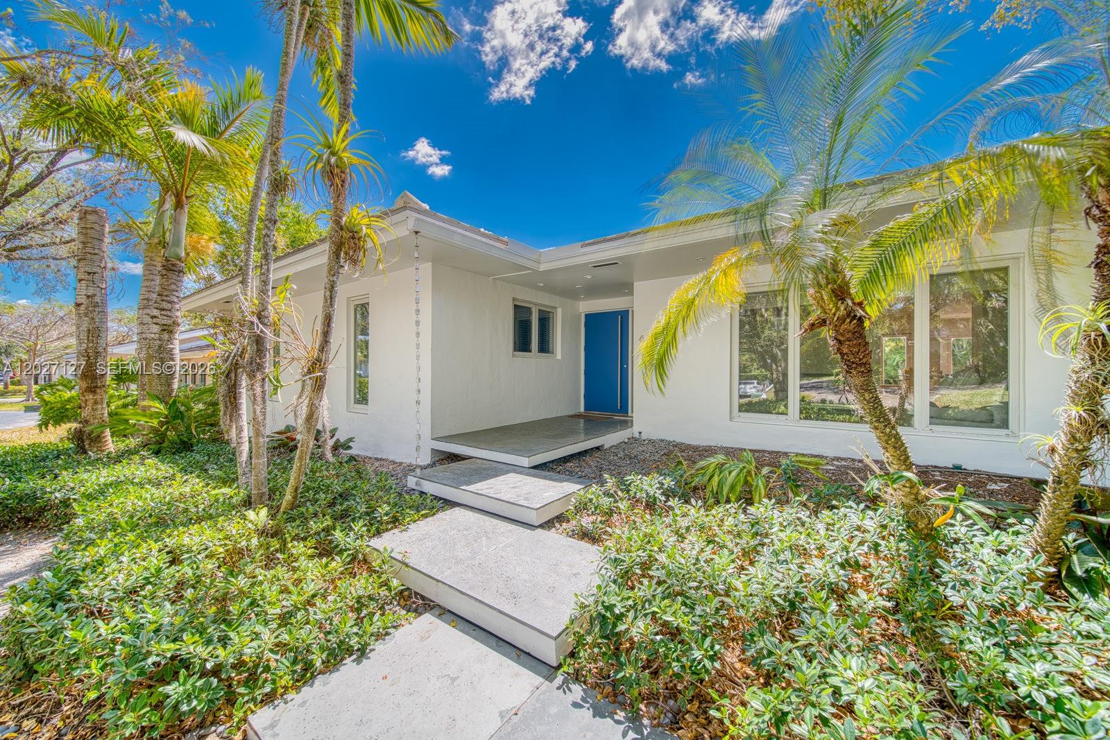 A white single-story house with a blue front door and palm trees in the yard — 620 Conde Ave, Coral Gables FL 33156, CORAL GABLES, FL