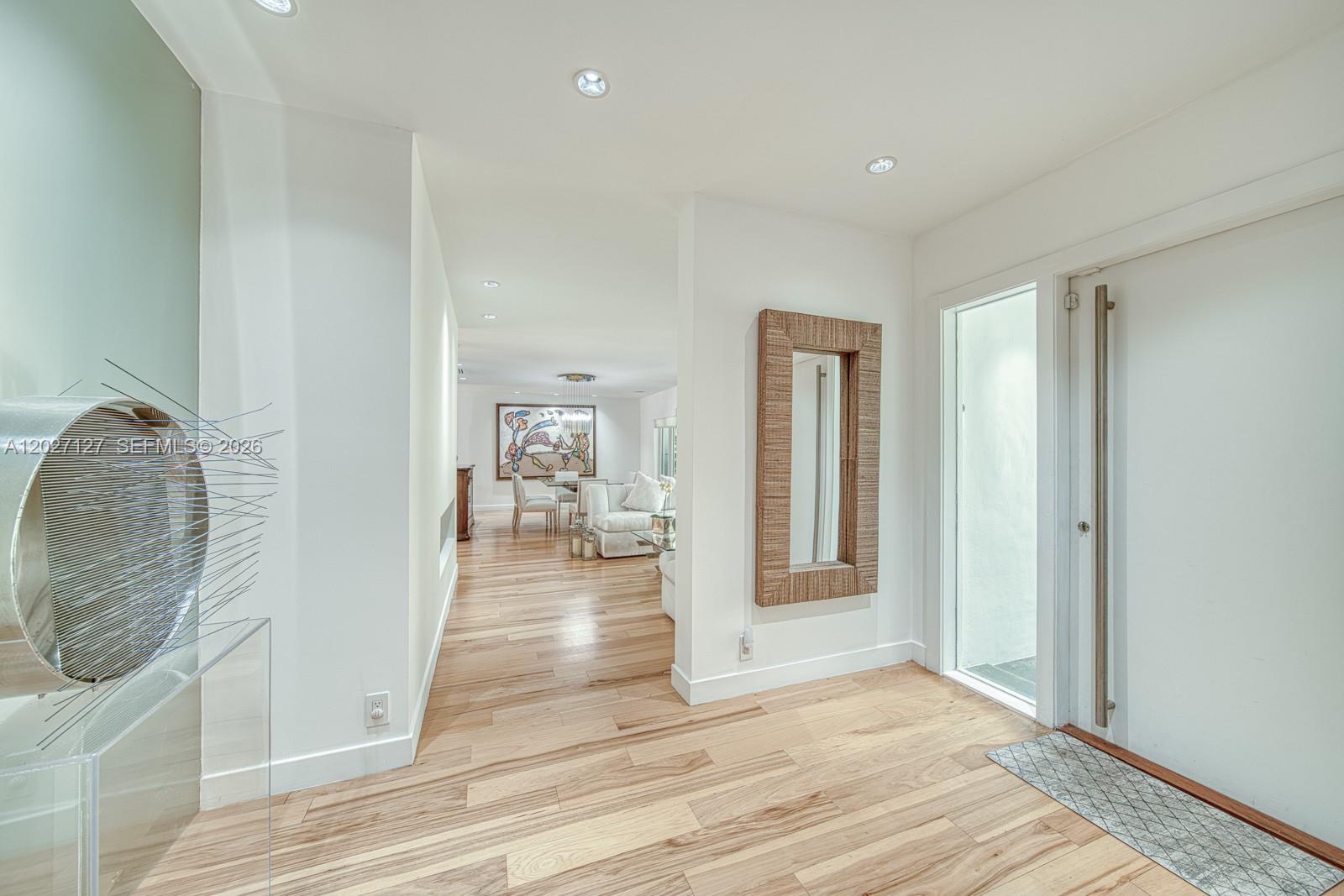 An entryway with light wood floors leads into a living area with white walls — 620 Conde Ave, Coral Gables FL 33156, CORAL GABLES, FL