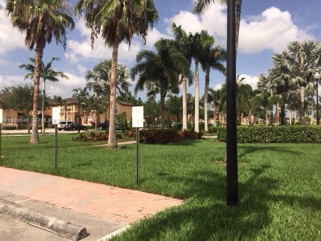 A grassy lawn with palm trees and a brick walkway in a residential community — 3360 NE 14th Dr # 30, Homestead FL 33033, HOMESTEAD, FL