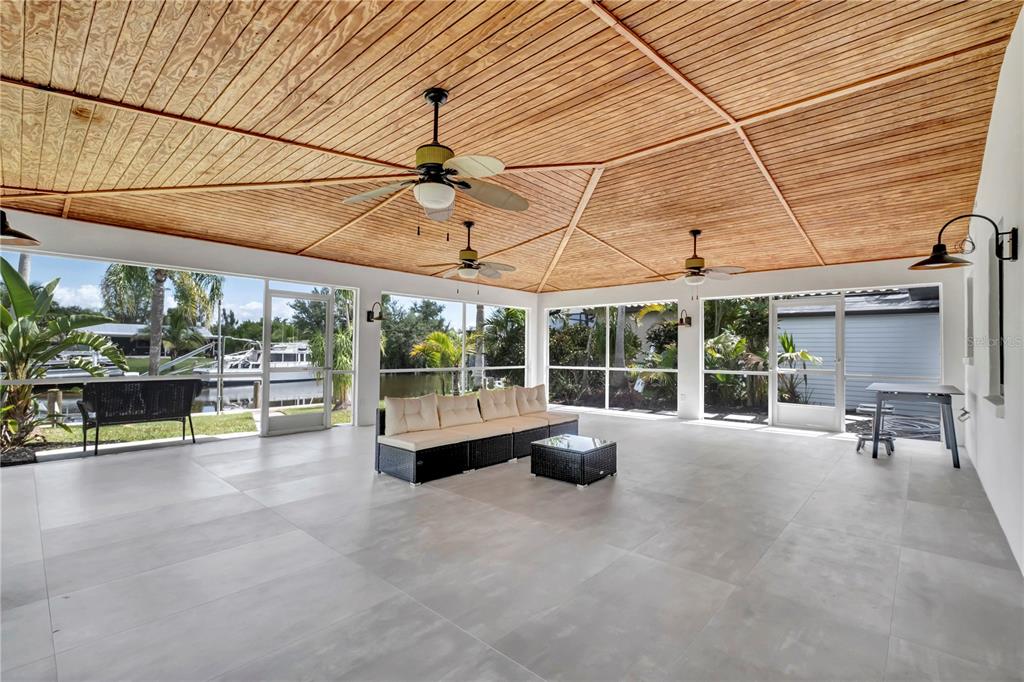 A spacious screened-in patio features a vaulted wood ceiling, ceiling fans, and large floor tiles — 15180 LYNEBURG AVENUE, PORT CHARLOTTE, FL