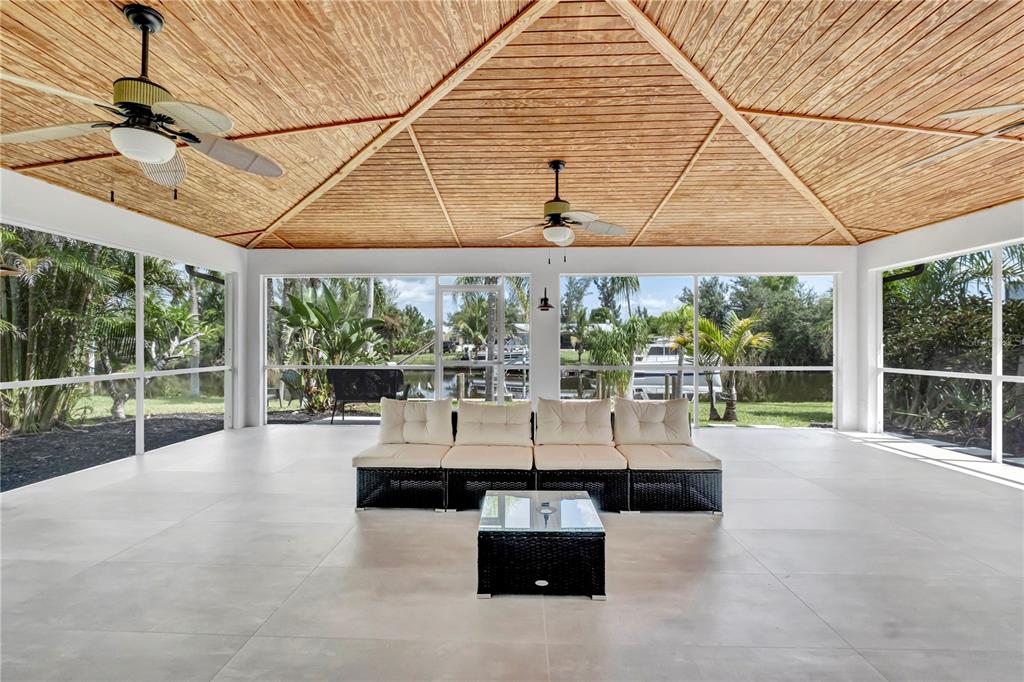 A screened-in patio features a vaulted wood ceiling, ceiling fans, and a view of water — 15180 LYNEBURG AVENUE, PORT CHARLOTTE, FL