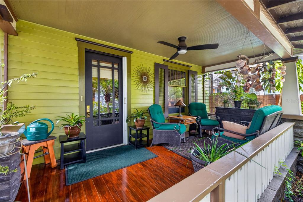 A covered front porch features lime green siding, a dark wood floor, and teal patio furniture — 652 8TH AVENUE N, ST PETERSBURG, FL