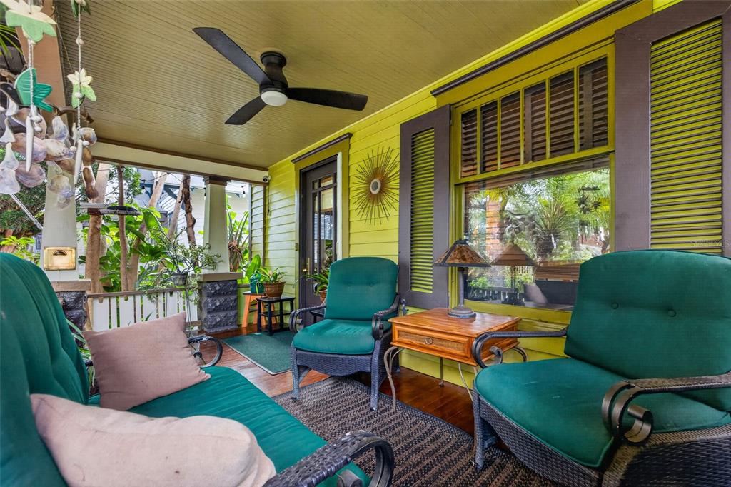 A covered porch features green wicker furniture, a ceiling fan, and lime green exterior siding — 652 8TH AVENUE N, ST PETERSBURG, FL