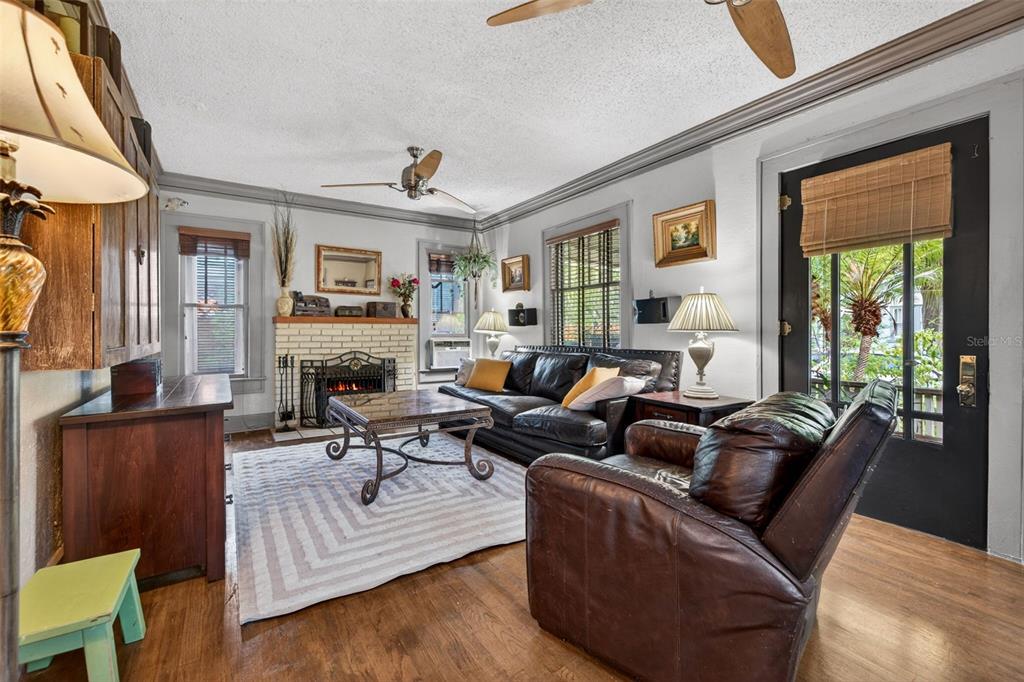 A living room features a brick fireplace, leather furniture, hardwood floors, and a ceiling fan — 652 8TH AVENUE N, ST PETERSBURG, FL