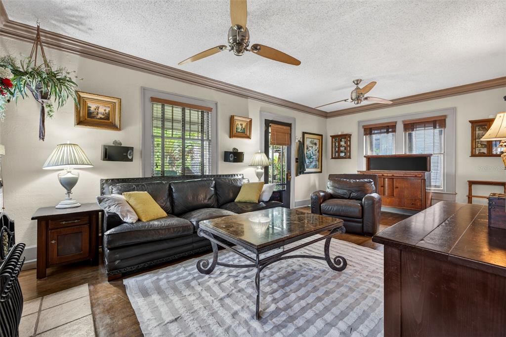 A living room with a leather sofa, coffee table, two ceiling fans, and hardwood floors — 652 8TH AVENUE N, ST PETERSBURG, FL