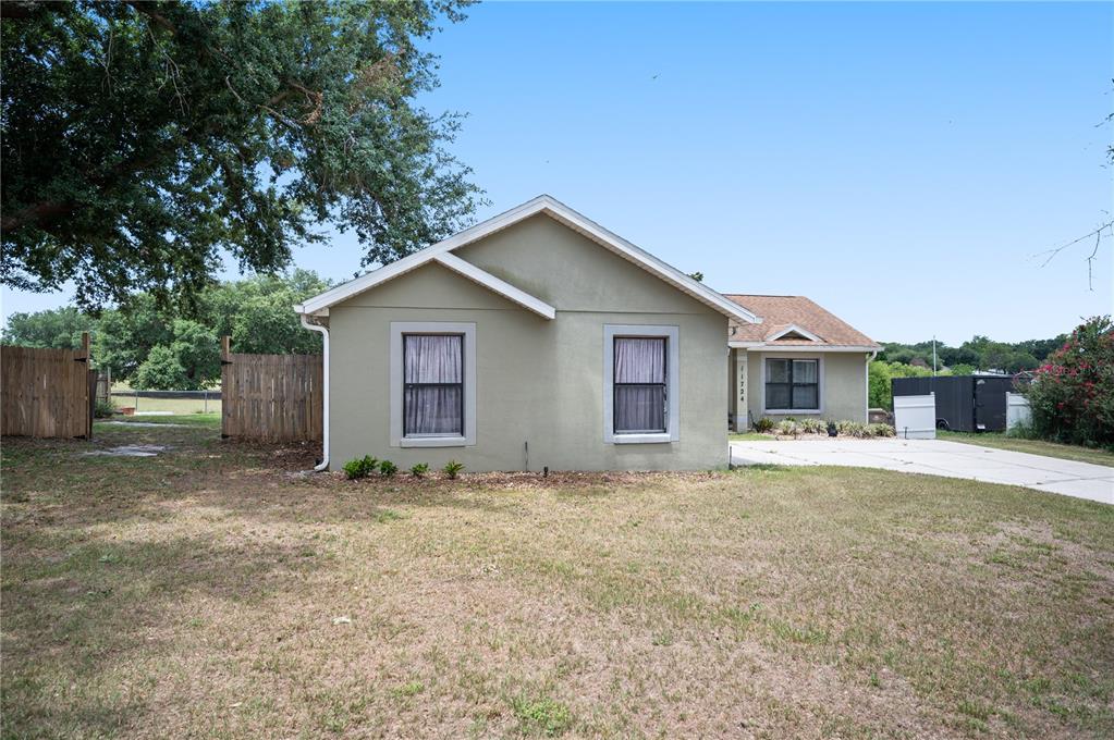 A single-story house with a light green stucco exterior and a concrete driveway — 11724 CONSTANCE WAY, CLERMONT, FL