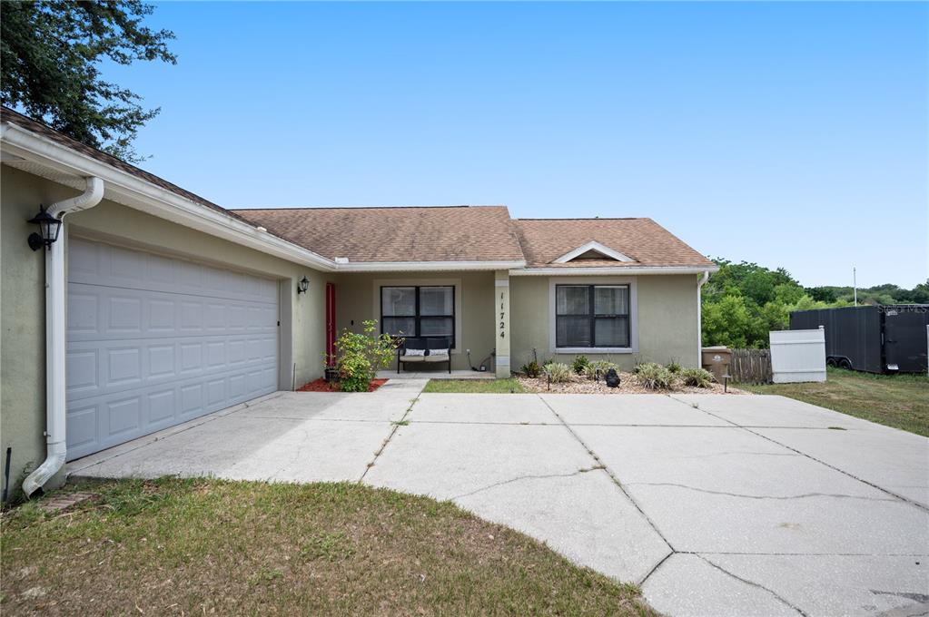 A single-story house with a concrete driveway, two-car garage, and a small front porch — 11724 CONSTANCE WAY, CLERMONT, FL