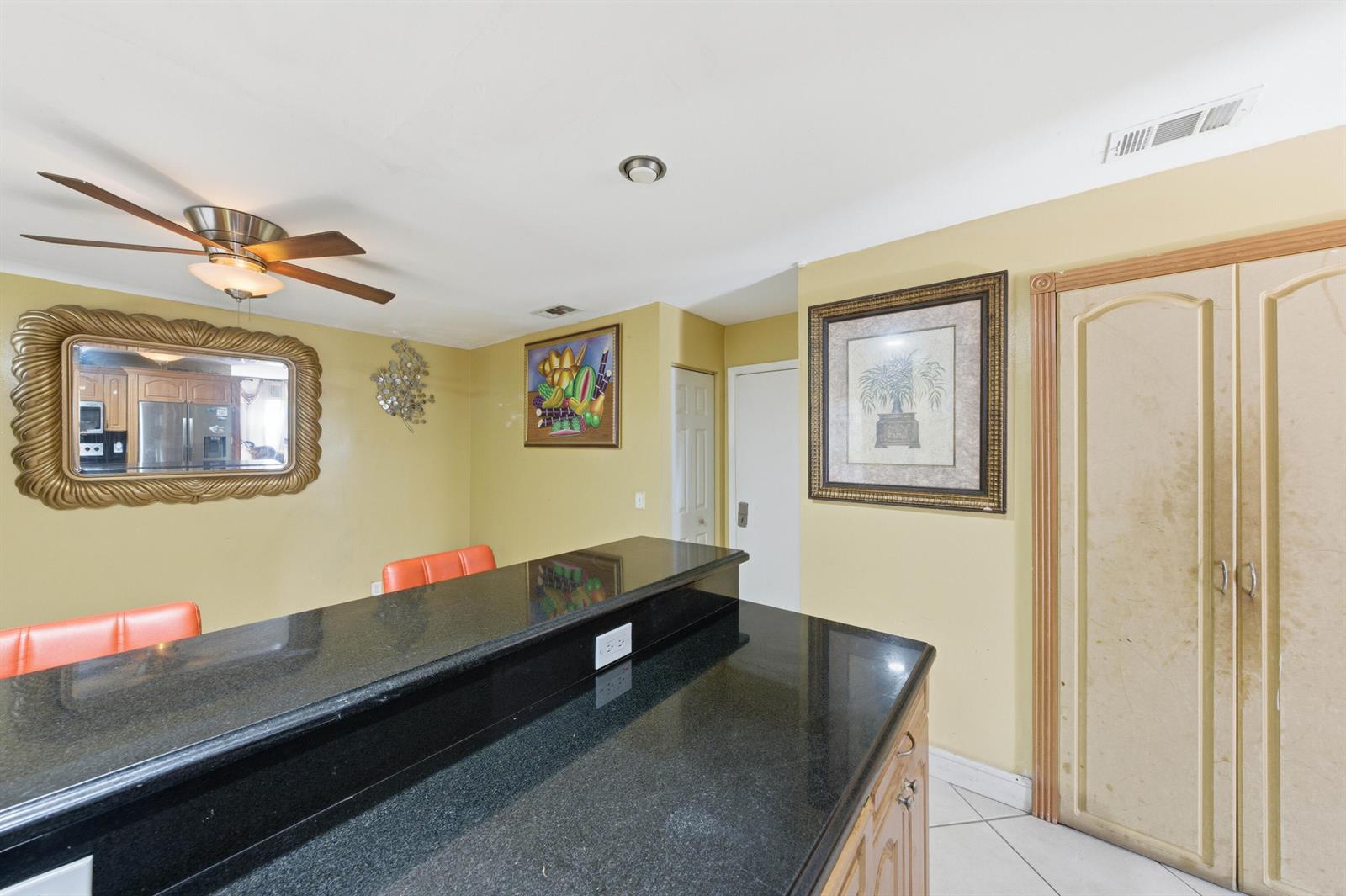 A kitchen features a black granite breakfast bar, yellow walls, and a ceiling fan — 6582 Bayfront Drive, Margate FL 33063, MARGATE, FL