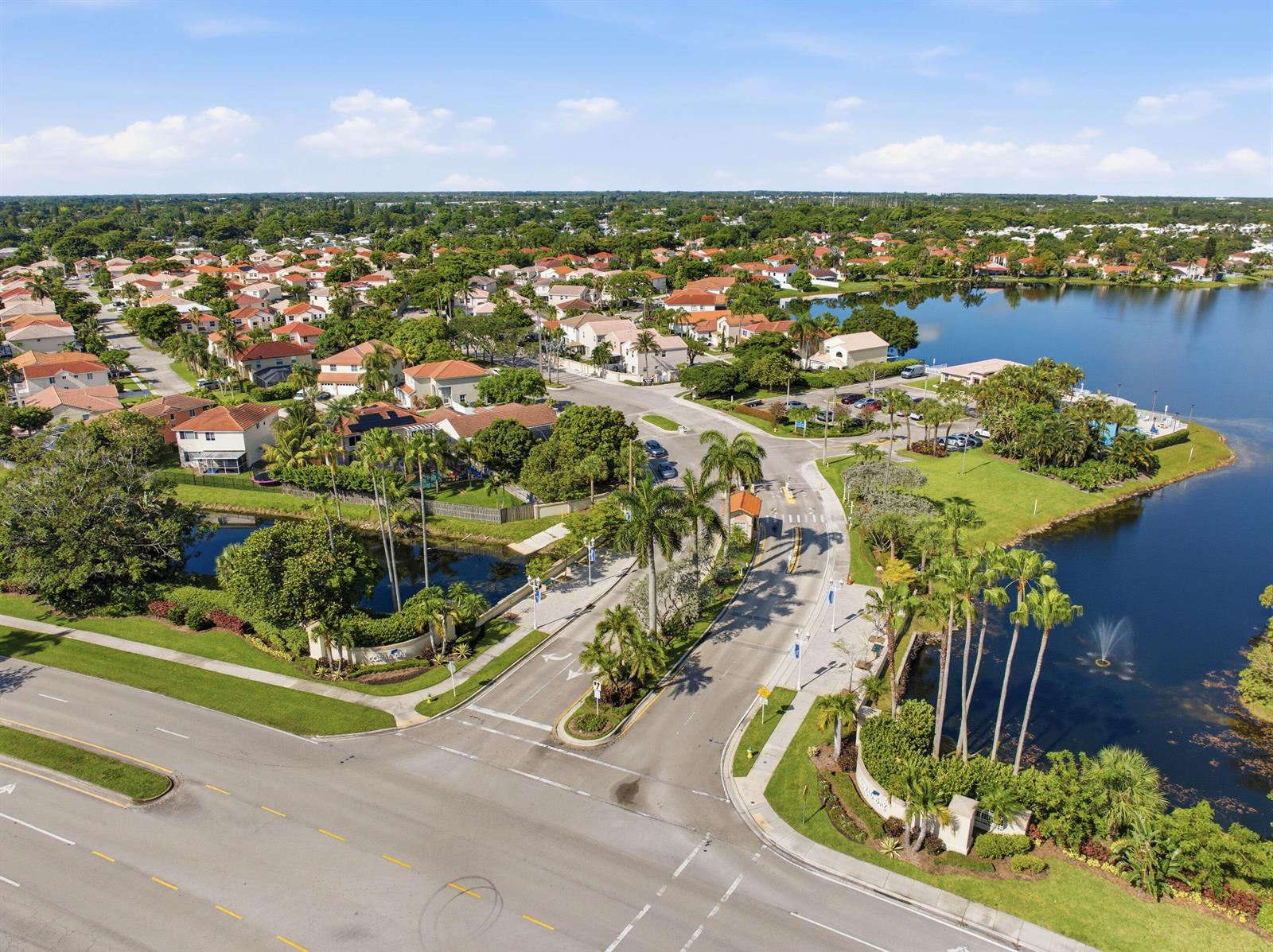 An aerial view shows a gated residential community entrance with palm trees and a lake — 6582 Bayfront Drive, Margate FL 33063, MARGATE, FL