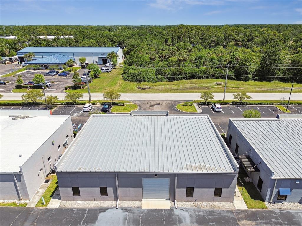 An aerial view shows a gray industrial building with a metal roof and parking lot — 13908 MONROES BUSINESS PARK, TAMPA, FL