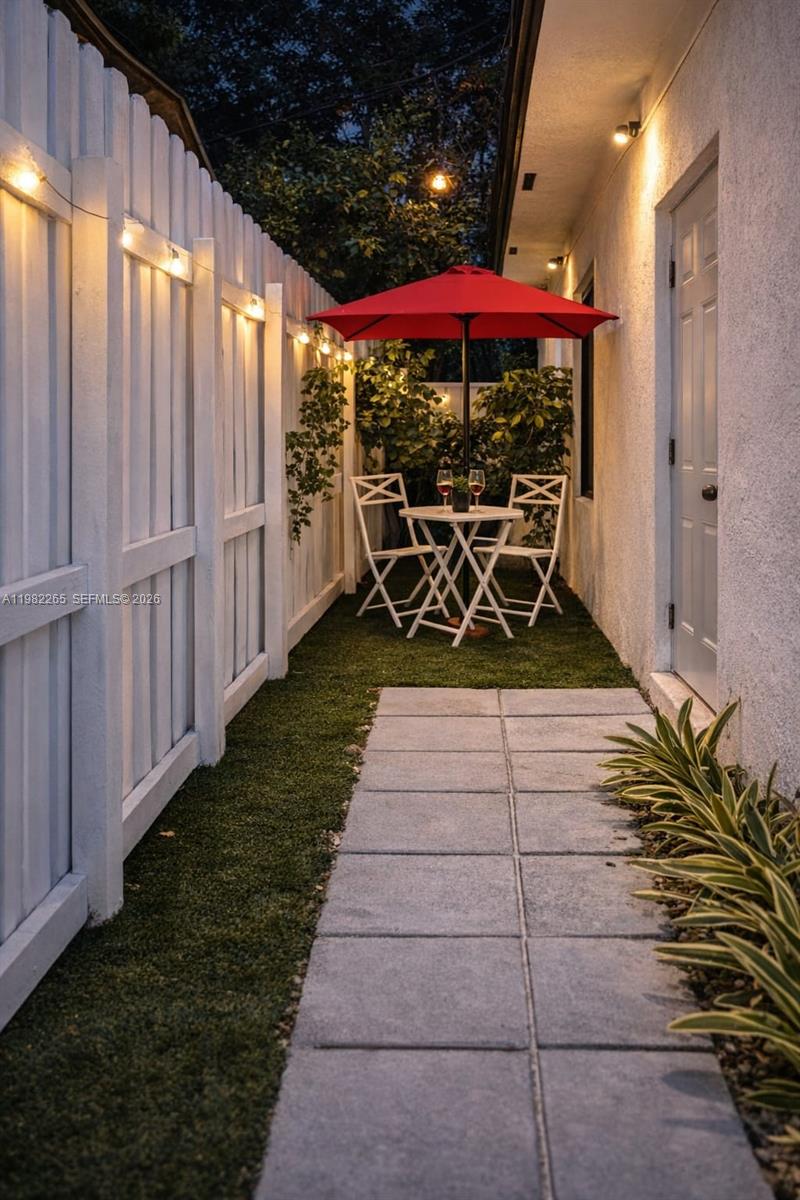 A narrow outdoor patio features a red umbrella, bistro table, chairs, and string lights — 613 NW 10th St # 2, Hallandale Beach FL 33009, HALLANDALE BEACH, FL