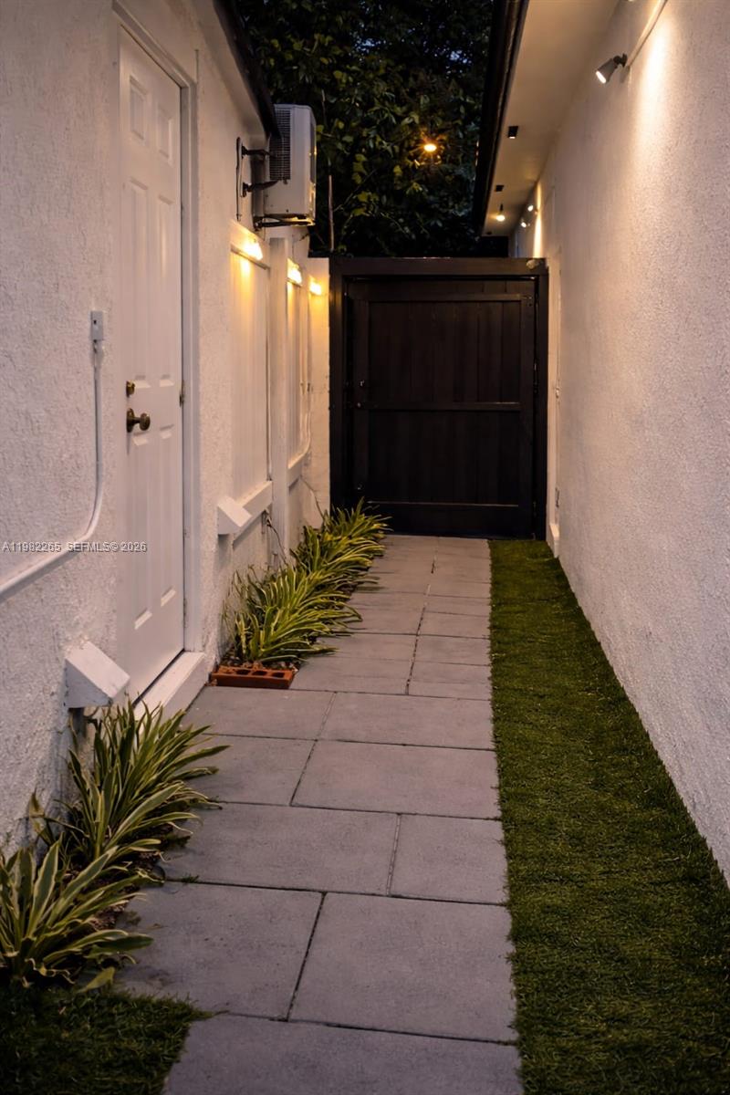 A narrow outdoor walkway features gray stone pavers, a strip of artificial turf, and plants — 613 NW 10th St # 2, Hallandale Beach FL 33009, HALLANDALE BEACH, FL