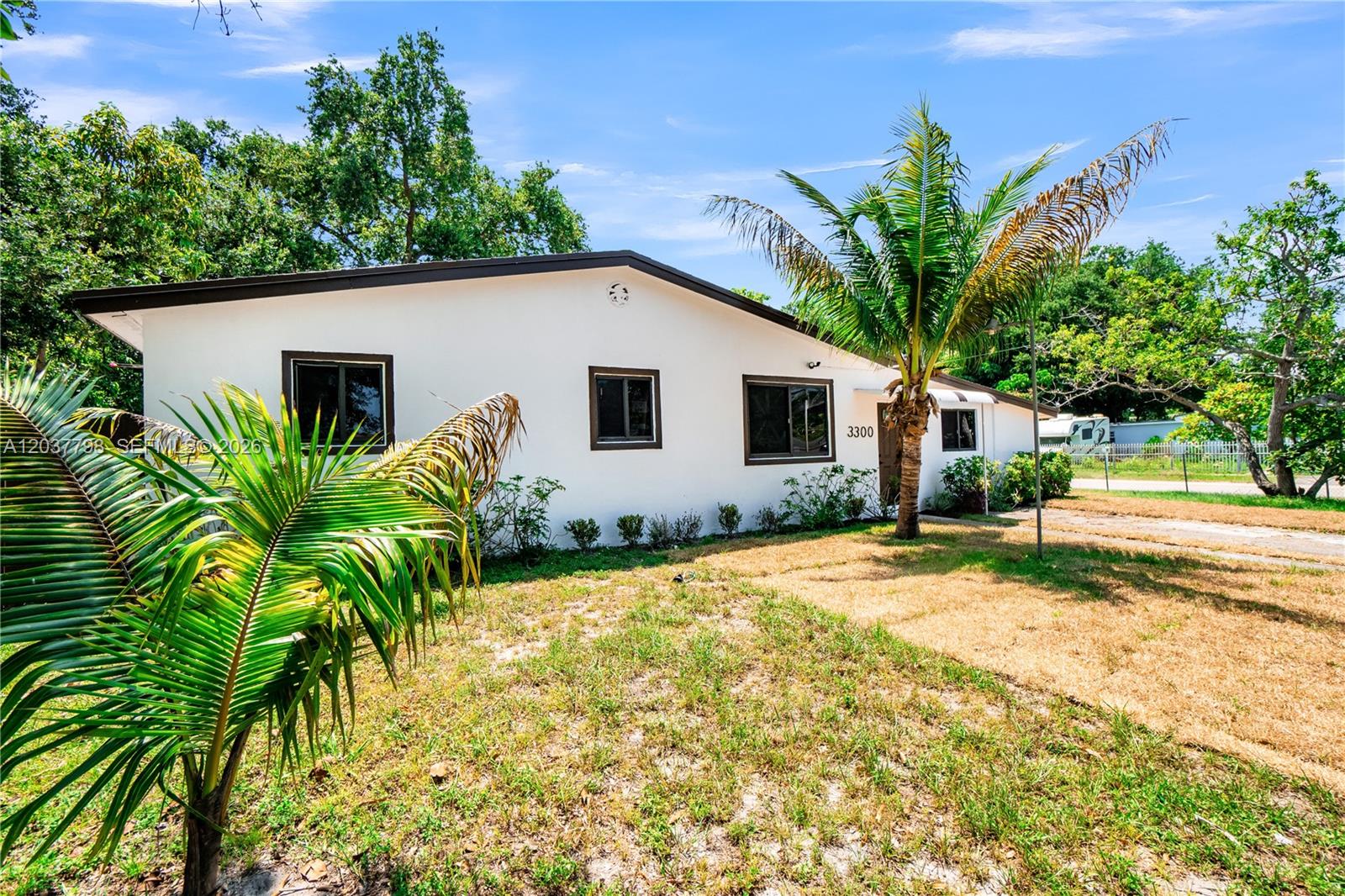 A white single-story house with brown trim and a palm tree in the front yard — 3300 SW 40th Ave, West Park FL 33023, WEST PARK, FL