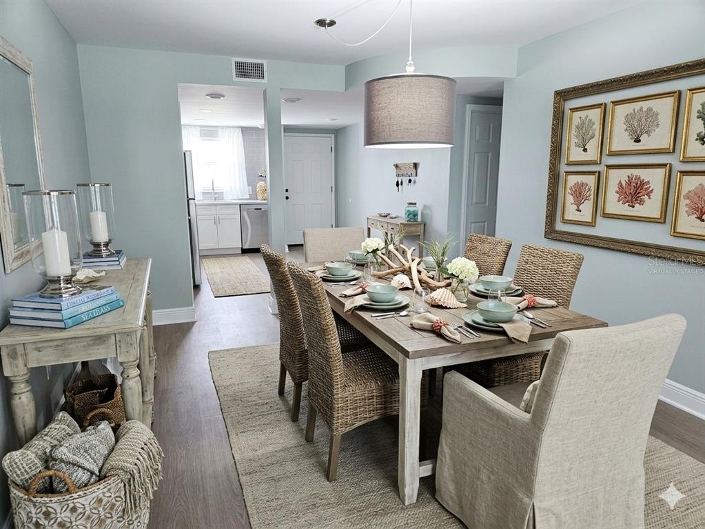 A dining room features a wooden table with woven chairs and light blue walls — 1819 SHORE DRIVE S UNIT 103, SOUTH PASADENA, FL