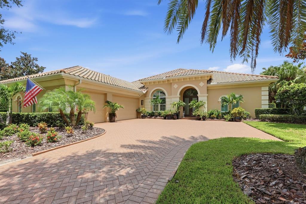 A single-story house with a paved driveway, a three-car garage, and an American flag — 3342 FOUNDERS CLUB DRIVE, SARASOTA, FL