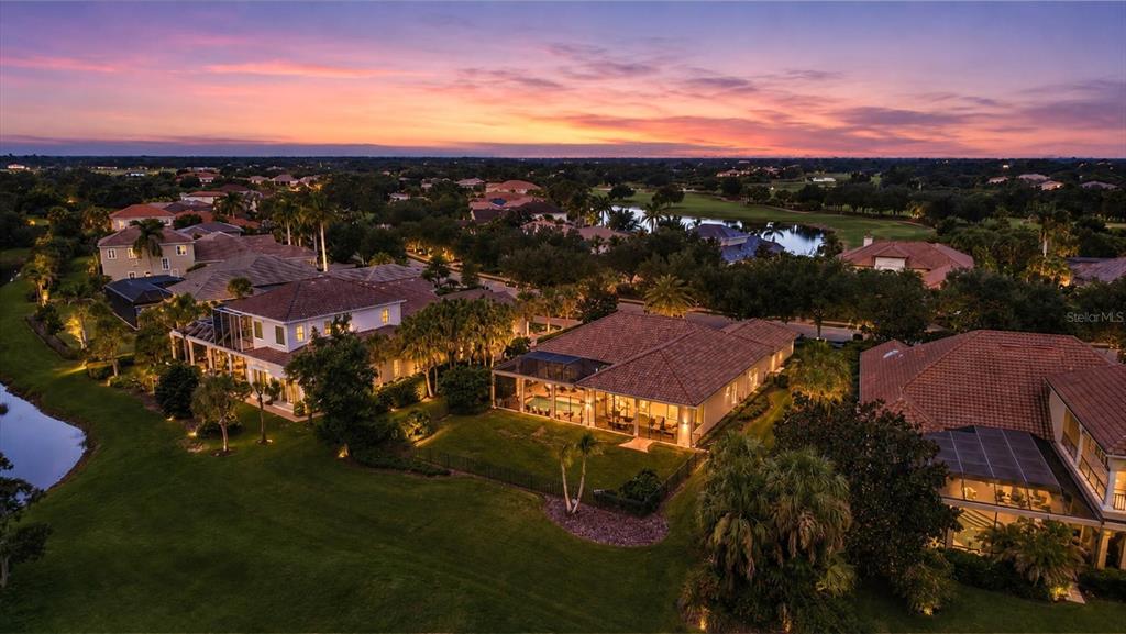 An aerial view of several suburban houses with tiled roofs and swimming pools at sunset — 3342 FOUNDERS CLUB DRIVE, SARASOTA, FL