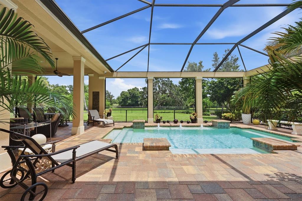 A screened-in patio features a swimming pool with water features and a paved deck — 3342 FOUNDERS CLUB DRIVE, SARASOTA, FL