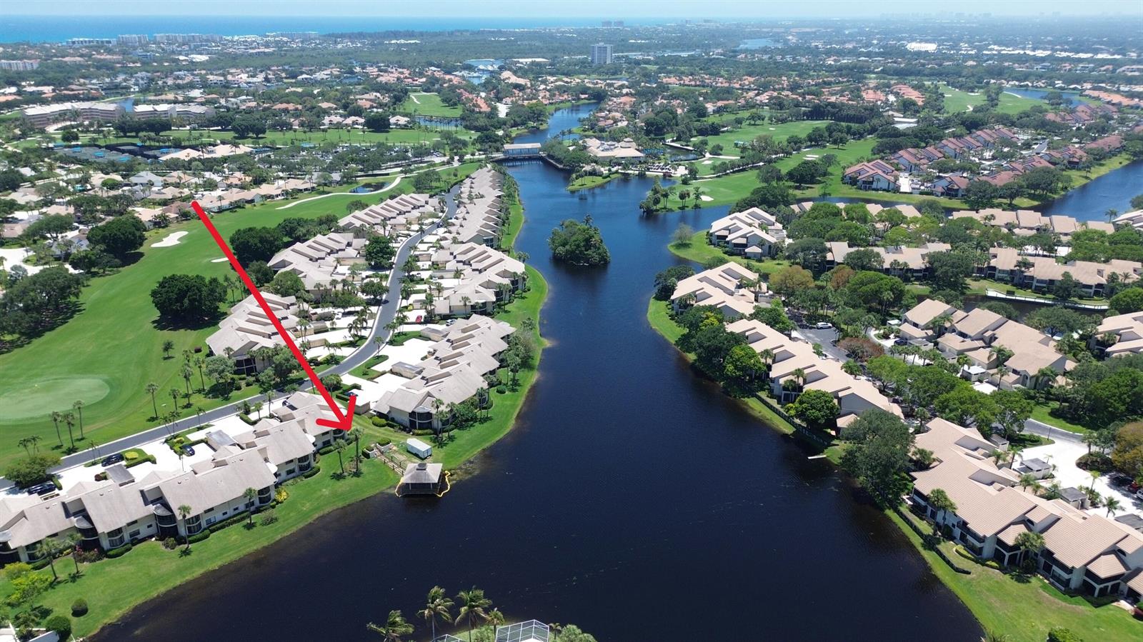 An aerial view shows a residential community with townhomes situated along a winding lake — 16997 Waterbend Drive # 139, Jupiter FL 33477, JUPITER, FL